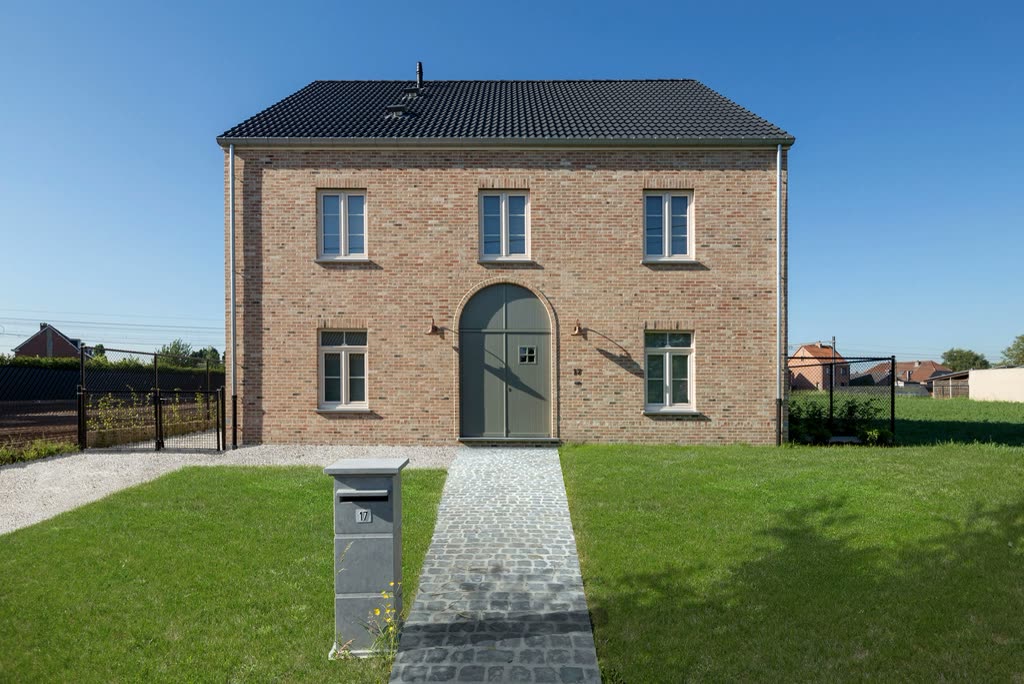 Finished two-storey brick house with an arched door and gravel path