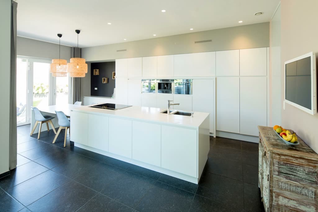 Bright renovated kitchen with a long white island and dark floor tiles