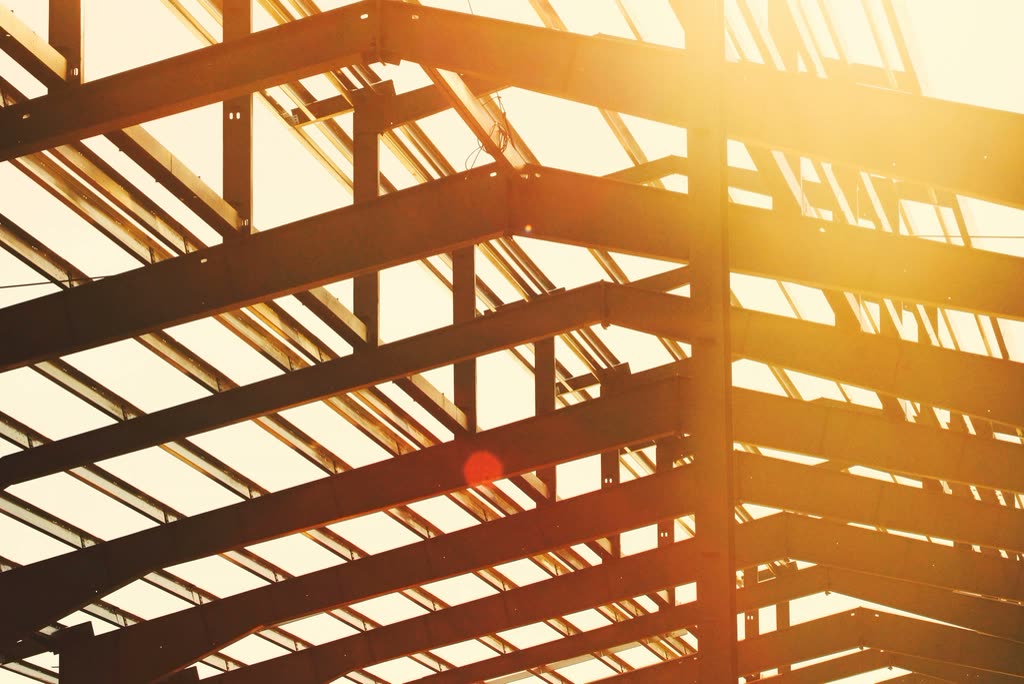 Steel frame beams lit by low sunlight on a construction site